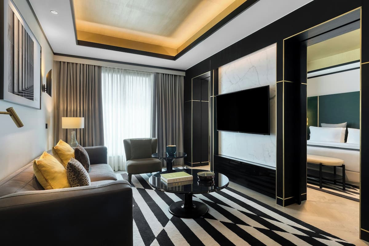 A modern hotel room with a sofa, coffee table, and a large flat-screen TV.