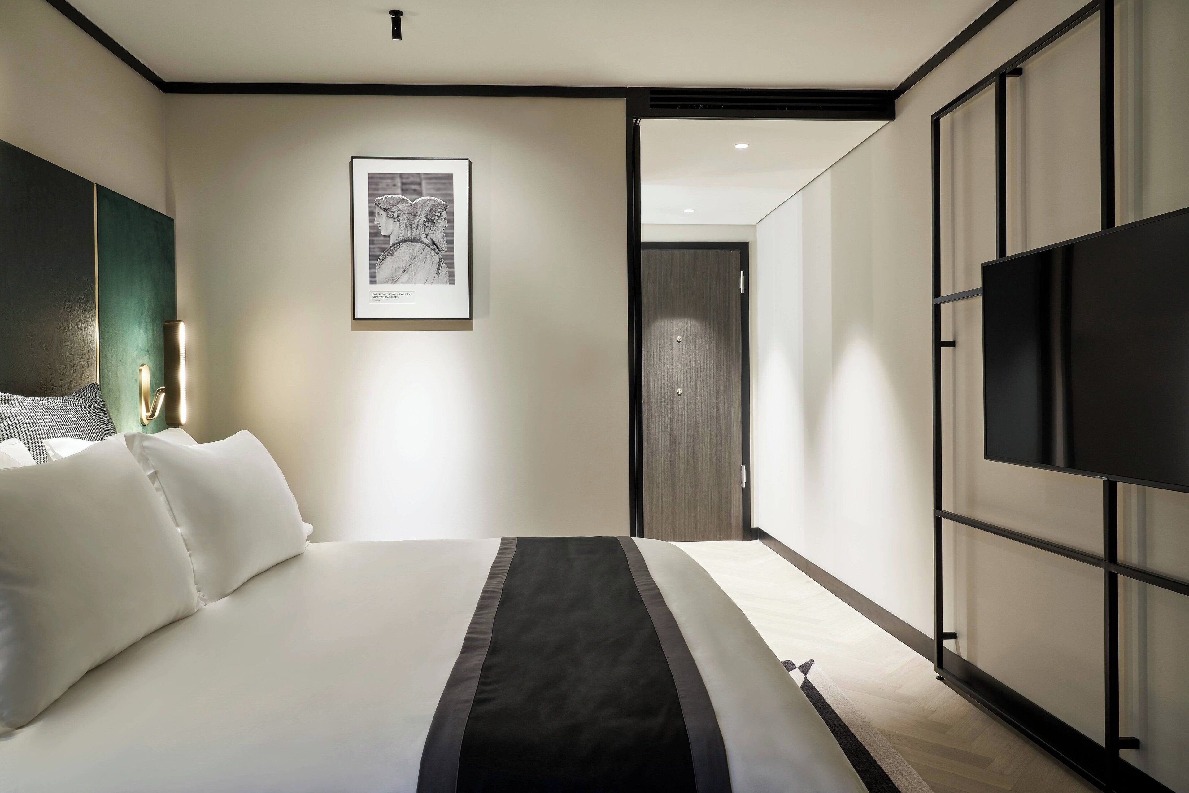 Habitación de hotel moderna con una cama grande, un televisor de pantalla plana y un cuadro en la pared.