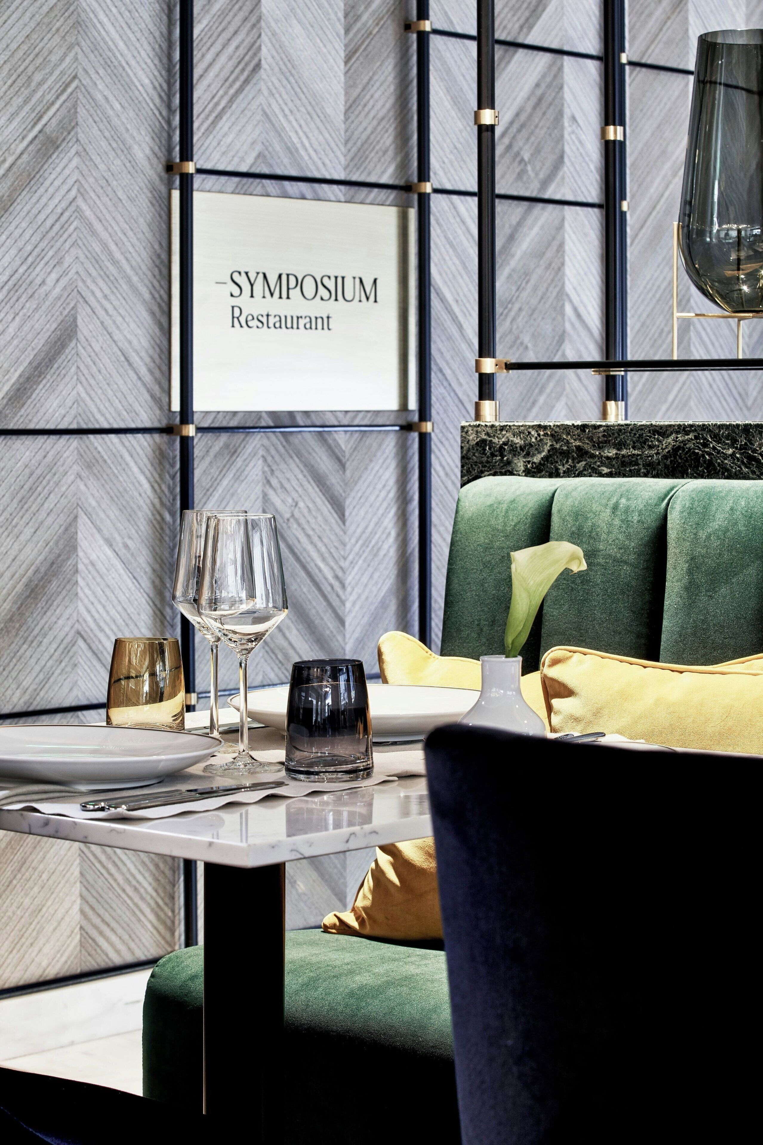 Ein Restaurantinnenraum mit einer Wisteria-Wand, einem dunkelgrünen Sofa und einem Tisch, gedeckt mit Weingläsern und Besteck.