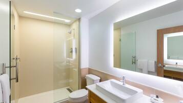 A modern bathroom with a glass-enclosed shower, a white sink, and a large mirror.
