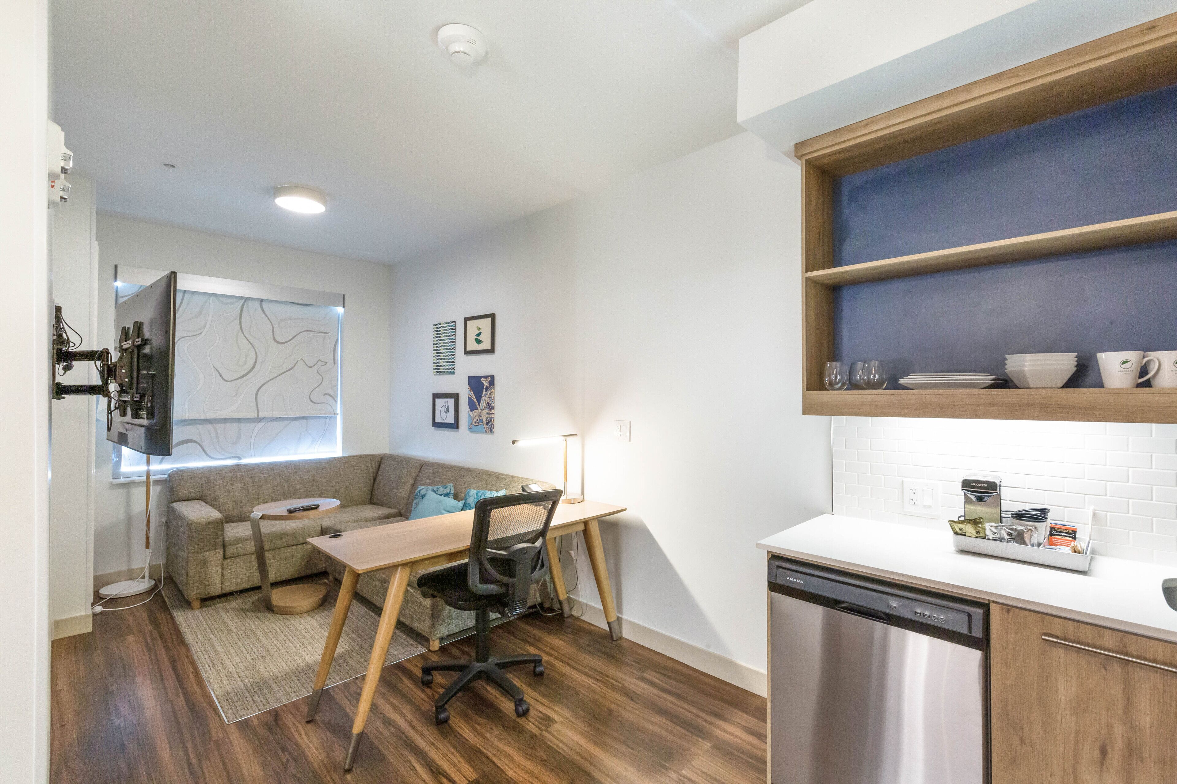 Een compacte leefruimte met een kitchenette, een eethoek met tafel en stoelen, een bank en een televisie.