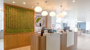 Un moderno mostrador de recepción con panel de madera y jardín vertical verde.