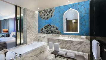 Uma casa de banho moderna com uma banheira grande, um lavatório com espelho e um banco com toalhas.