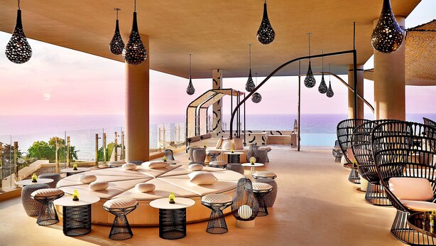 Un salón en la azotea con asientos y mesas, con vistas al mar.