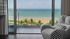 Una habitación con vista a la playa, una silla a rayas y un ventanal de vidrio.