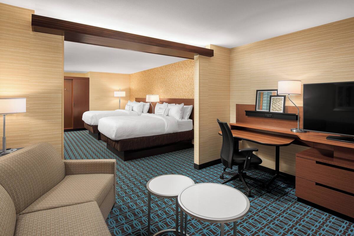 Une chambre d’hôtel comprenant un lit, deux tables de chevet, un bureau avec une chaise, une télévision et un canapé.