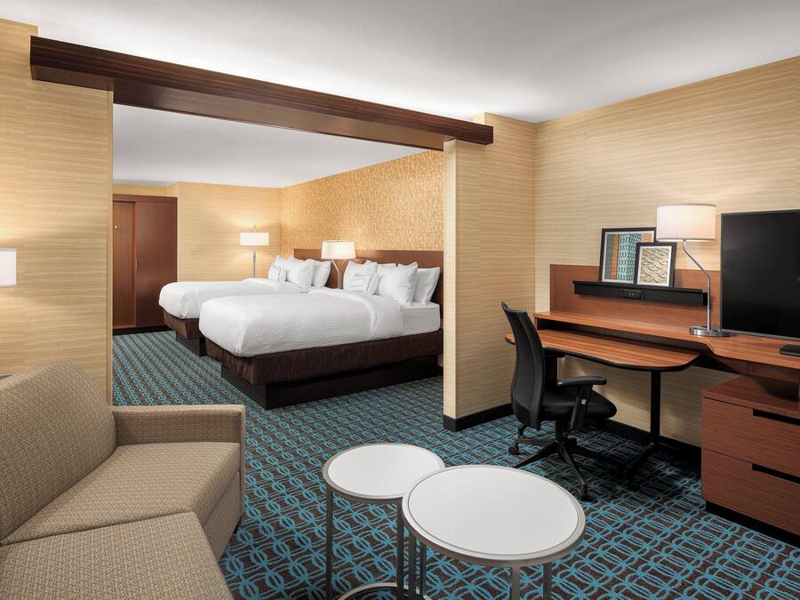 A hotel room with a bed, two bedside tables, a desk with a chair, a TV, and a sofa.