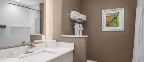 A modern bathroom with a white sink, a mirror, a toilet, and a towel rack.
