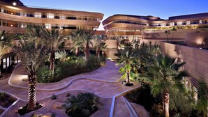 A modern building with curved architecture and a central courtyard with palm trees and a winding pathway. - Marriott Riyadh Diplomatic Quarter (Riyadh)