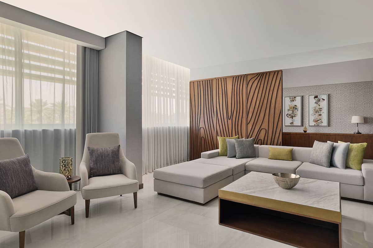 A modern living room with a sectional sofa, two armchairs, a coffee table, and a decorative wall panel.