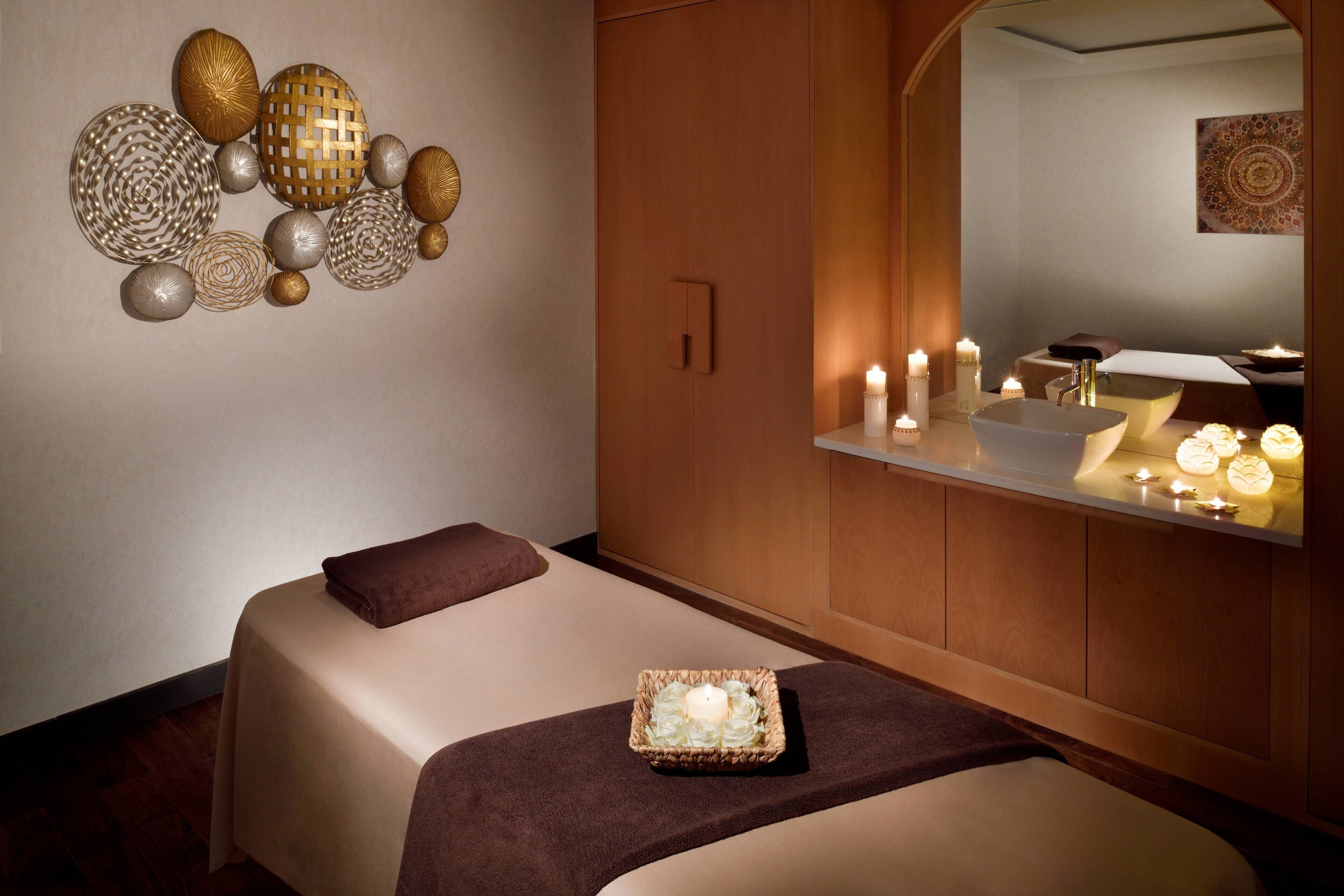 Un moderno spa con cama, espejo, velas y decoración de pared.