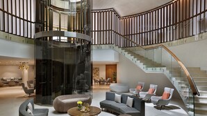 A spacious lobby with a curved staircase, modern seating, and a central elevator. - Marriott Riyadh Diplomatic Quarter (Riyadh)