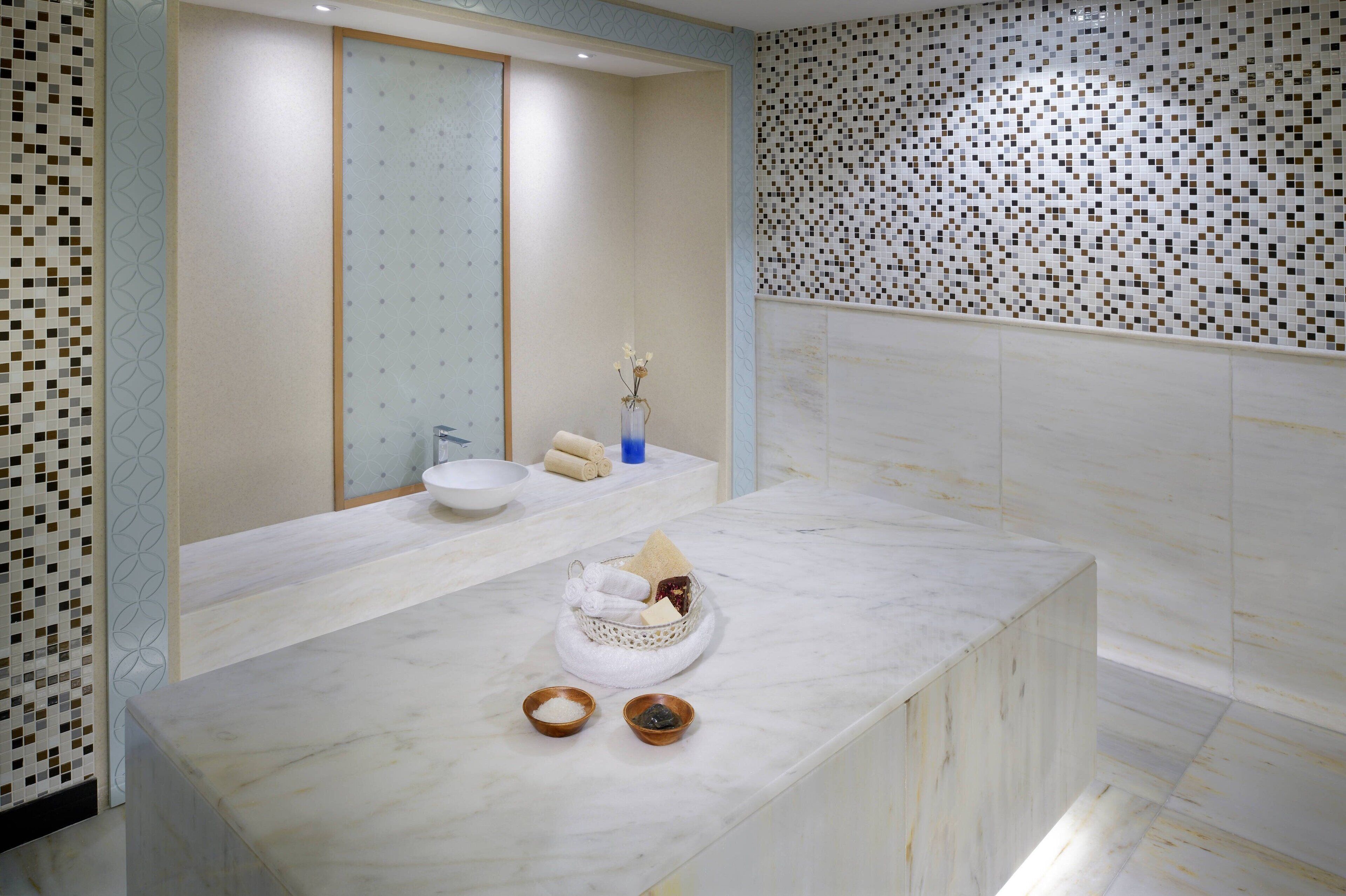 A bathroom with a marble countertop, a sink, and a mirror.