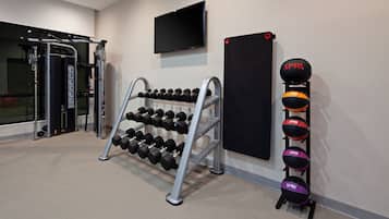 A gym with dumbbells, a TV, and exercise equipment.