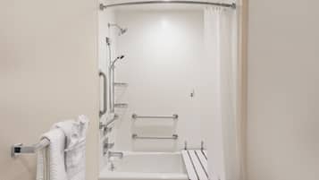 Un baño moderno con cabina de ducha, barras de apoyo y un perchero.