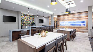 Un espace bar moderne doté d’un long comptoir, de nombreux sièges et d’une grande fenêtre offrant une vue panoramique.