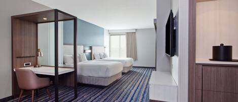 A hotel room with a bed, a desk, a chair, a TV, and a bathroom.
