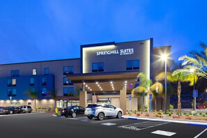A hotel with a modern facade, labeled "Springhill Suites by Marriott," featuring a parking lot with several cars and a well-lit entrance. - SpringHill Suites by Marriott Escondido Downtown (Escondido)
