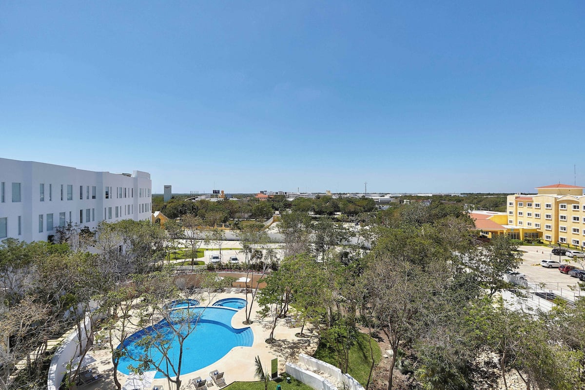 Ein Resort mit großem Schwimmbecken, umgeben von Bäumen und Gebäuden.
