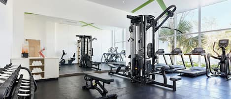 Un gimnasio moderno con diverso equipo de ejercicio, amplias ventanas y un diseño limpio y espacioso.