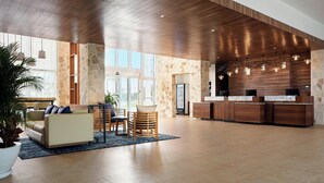 Un lobby espacioso con techo de madera, paredes de piedra, mostrador de recepción y zona de estar.