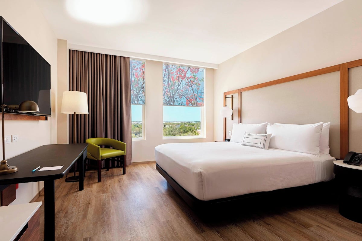 Ein Hotelzimmer mit Bett, Schreibtisch, Stuhl, Fernseher und großen Fenstern mit Blick.