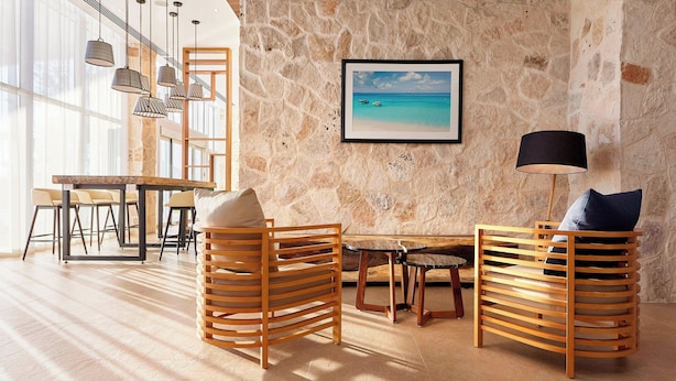 Una habitación con pared de piedra, muebles de madera, un cuadro enmarcado y lámparas colgantes.