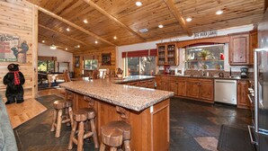 A spacious kitchen with wooden cabinets, a granite countertop, and a central island with stools.