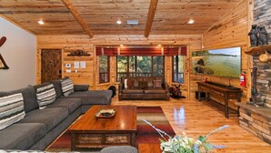 A log cabin interior with a sofa, coffee table, and a television.