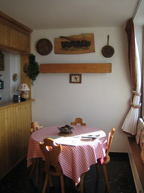 A dining area with a wooden table and chairs, a checkered tablecloth, and a rustic wall decor. - STUDIO CABIN 33m2 RESIDENCE LES CHAVONNES (la rosiere)