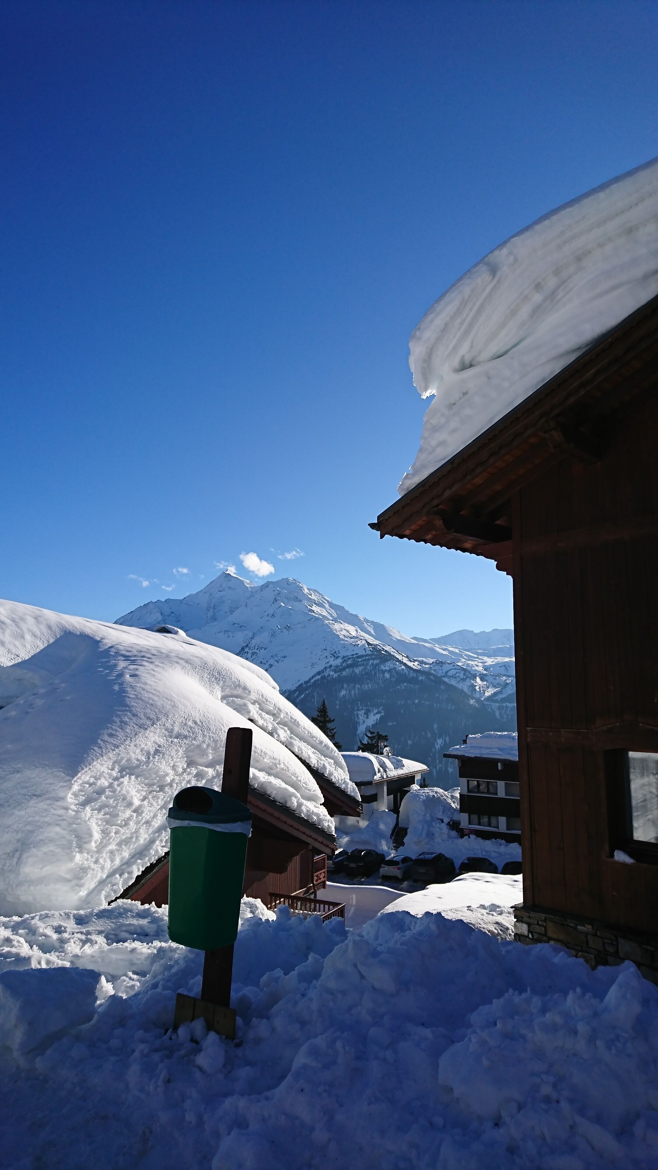 A snow-covered mountain with a wooden building in the foreground.
