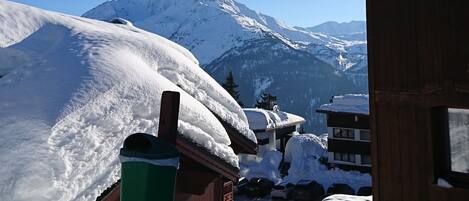A snow-covered mountain with a wooden building in the foreground.