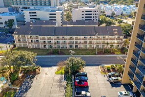 A multi-story hotel with a central courtyard, parking lot, and surrounding greenery. - Steps to the beach daily rentals pool washer dryer onsite two balconies full kitchen (Myrtle Beach)