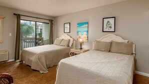 A hotel room with two beds, a balcony with curtains, and artwork on the walls. - Steps to the beach  daily rentals pool washer dryer onsite two balconies full kitchen (Myrtle Beach)