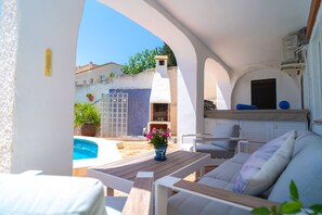 Un patio con piscina, posti a sedere all'aperto e vista su un edificio con parete piastrellata e camino.