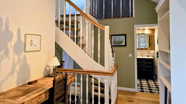 A staircase with white balusters, a chandelier, and a wooden desk with drawers. - HR Cottage am Honigbach in the center of Coesfeld (Coesfeld)