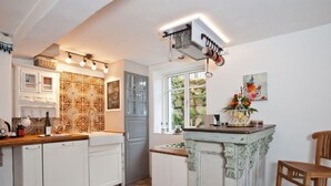A kitchen with white cabinets, a patterned backsplash, and a window with a view of greenery. - HR Cottage am Honigbach in the center of Coesfeld (Coesfeld)