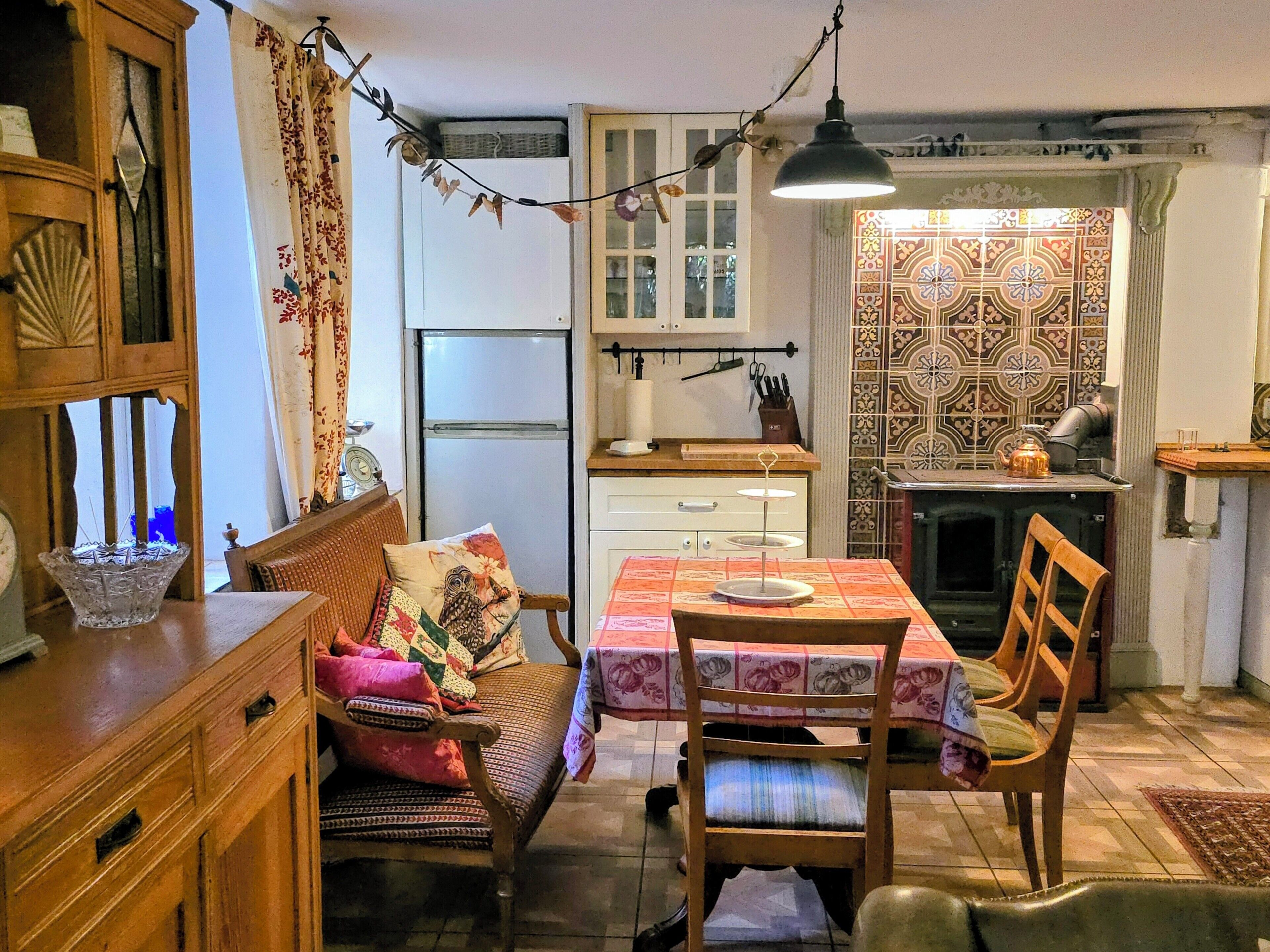 Une cuisine chaleureuse avec un coin repas, des meubles en bois, un réfrigérateur et un crédence décorée.
