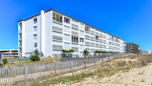 Un hôtel à plusieurs étages, doté d’une façade blanche, de balcons et bordé d’une plage de sable au premier plan.