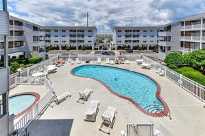 Relax by the hotel's central oval pool surrounded by lounge chairs and lush greenery.