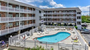 Ein mehrstöckiges Hotel mit Swimmingpool und Sitzbereich im Freien.