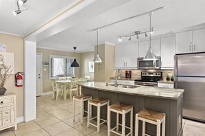 Enjoy cooking in this well-equipped kitchen with a central island, sink, and bar stools.