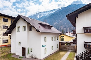A white building with multiple windows and a sloped roof, surrounded by other buildings and a mountainous backdrop. - Das AlpenLoft _Mountain View_4 km from skiing area (Mallnitz)