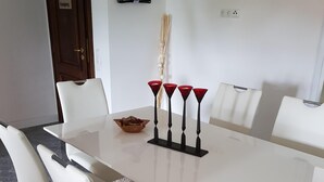 Un comedor moderno con una mesa blanca, cuatro sillas y un cuenco decorativo.