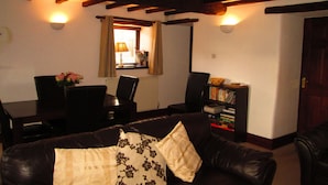 Ein gemütliches Wohnzimmer mit einem dunkelbraunen Ledersofa, einem Holztisch und einem Bücherregal.