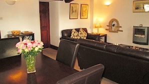 Ein Essbereich mit Tisch, Stühlen, einem Blumenstrauß, einer Couch und einem Kamin.