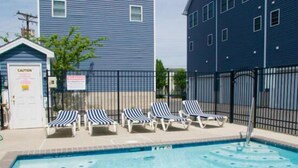 A swimming pool with lounge chairs and a caution sign.