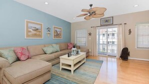 A living room with a beige sofa, a coffee table, and a ceiling fan.