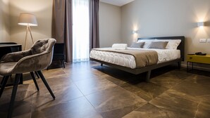 Una habitación de hotel moderna con una cama, una silla, un escritorio y una lámpara.