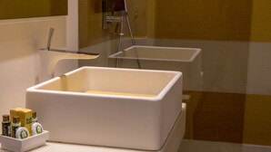 Un baño con una bañera blanca grande, un espejo y un pequeño estante con artículos de aseo.